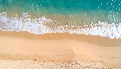 Aerial view of turquoise ocean waves meeting a sandy beach with footprints