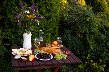 Garden table setting with wine, cheese, and fruits for a relaxing evening
