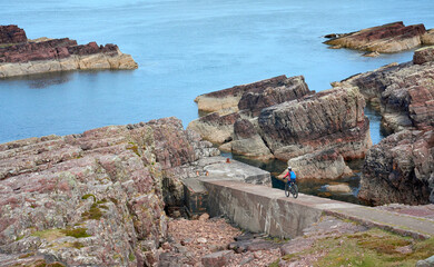 active senior woman riding her electric mountain bike on the cliffs near Rua Reidh Lighthouse next...