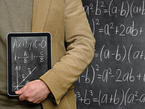 Teacher holding a Tablet Computer in front of a chalkboard