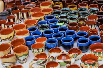 Obraz premium Colorful handmade ceramic pots and mugs on display at a street market. Traditional pottery in various shapes, sizes, and patterns.