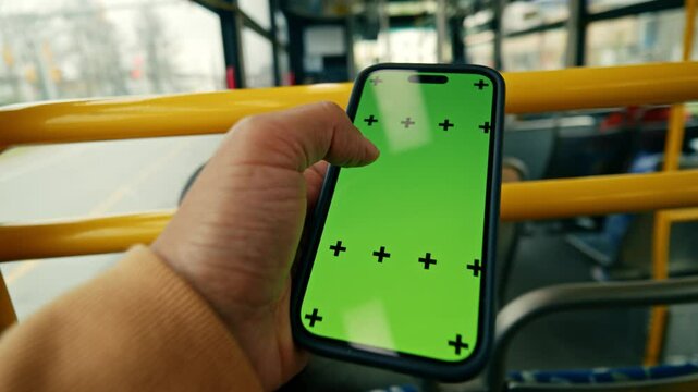 POV Shot Of Green Screen Smartphone Used At City Bus Station Urban Background With City Lights And Vehicles. Man Holding Phone With Chroma Key. Transport Technology Scene.