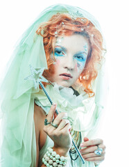 A charming red-haired woman in a New Year's costume of a fabulous fairy holds a magic wand.