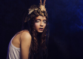 Close up portrait of young woman with bright makeup, braids and a skull on her head