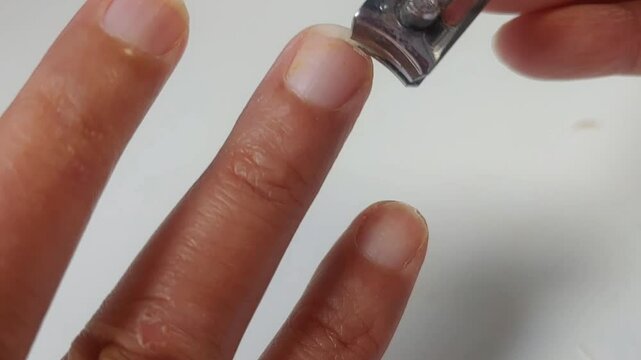 close up of someone cutting nails using a nail clipper isolated on white background 