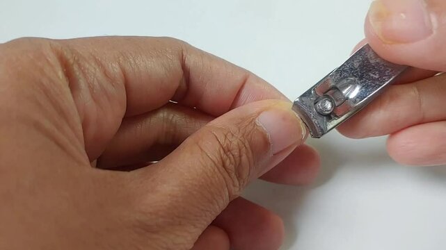 close up of someone cutting nails using a nail clipper isolated on white background 