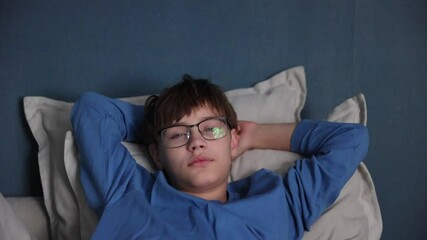 teenage depression. A sad teenager with glasses is sitting on the couch hugging his knees. the crisis of adolescence