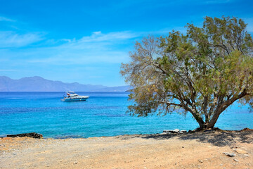  A boat floating near in a peaceful Mediterranean beach with turquoise water, rocky hills in the background.