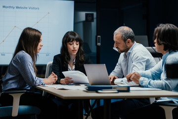 Business executives and assistants brainstorming investment risk evaluation in corporate boardroom