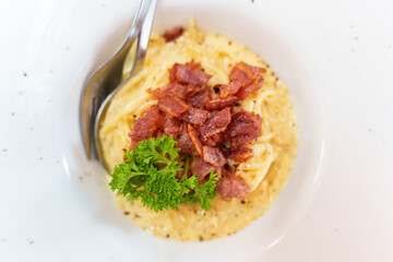 Creamy carbonara spaghetti with crispy bacon and parsley garnish