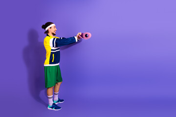 Young athlete in retro sportswear holding a pink yoga mat against a vibrant purple background,...