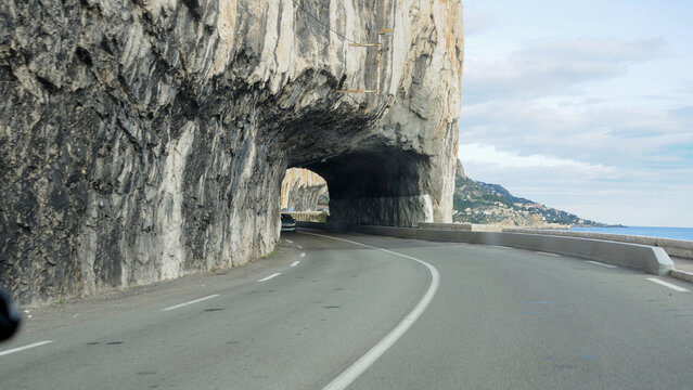 Coastal road tunnel carved into rocky cliffs in Monte Carlo, Monaco, revealing breathtaking Mediterranean views and scenic landscapes