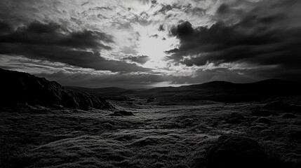 Dramatic black and white landscape photo of a sunlit, cloudy sky over a vast, mossy moorland
