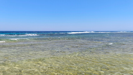 Natural background with sea view with underwater coral reef of Red Sea in Egypt. Clear day, clean blue sky, sunny day. Ideal for summer tourism and recreation.