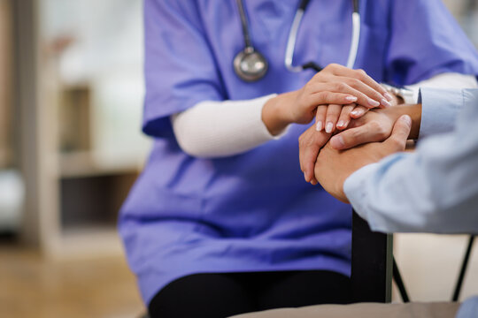 A female nurse hand caregiver holds senior patient's hands, and comfort an elderly. Doctor helping For care senior man and trust in nursing homes
