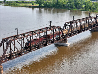 Aerial view of a Railroad locomotive pulling a freight train across the Mississippi river on a trestle bridge