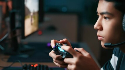 Young Asian man intensely playing video games with headset - Powered by Adobe