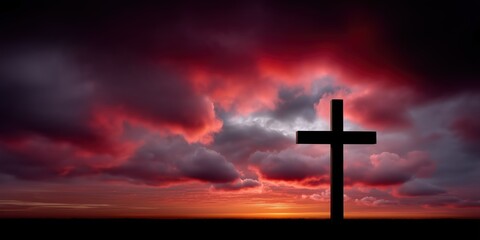 Silhouette of a christian cross standing alone in the middle of a wide open field under a beautifully lit sky depicting peace and solitude