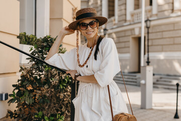beautiful woman walking in street on vacation dressed in white summer fashion dress