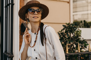 beautiful woman walking in street on vacation dressed in white summer fashion dress