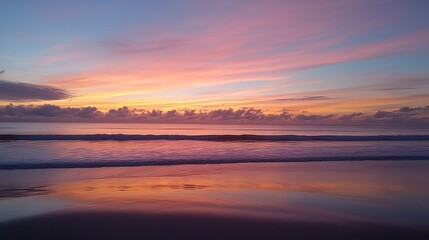 Naklejka premium Serene sunset over a tranquil ocean, reflecting vibrant colors in the calm waters. The sky showcases a breathtaking display of pink, orange, and purple hues