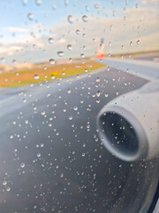 A plane is on the runway with raindrops on the window