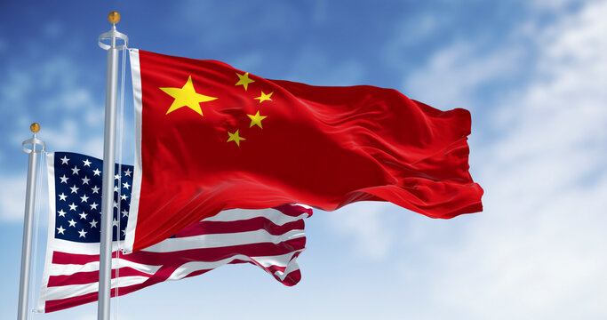Chinese and American flags waving together against blue sky. 3D render