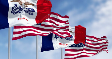 Naklejka premium Iowa state flag waving in the wind with the US flag on a clear day