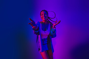 Vibrant portrait of a young woman enjoying dance in vivid neon lighting, expressing happiness and energy with lively poses