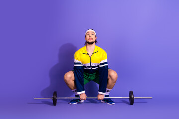 Young male athlete in colorful retro outfit preparing for weightlifting exercise on a vibrant...