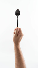 Black spoon held in hand on white bg