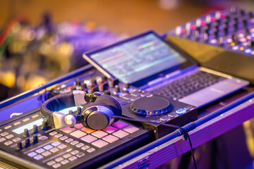 Professional DJ equipment setup with laptop, headphones and controller pads under club lighting. Concept of music production, electronic sound and nightlife. © Samir