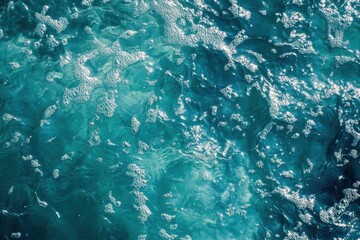 Top view of ocean surface with white sea foam and sun reflections. Clear turquoise water. Natural texture. Clean and refreshing summer atmosphere. Perfect for backgrounds and nature concepts. Banner