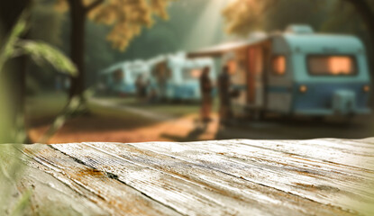 Empty wooden table with copy space, camping trailers and trees in the background. Vacation vibes, outdoor travel and product placement concept. Peaceful outdoor lifestyle, travel-friendly atmosphere.