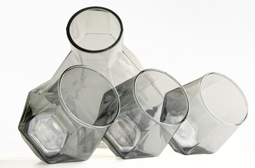 Modern decanter and three angled whiskey glasses in tinted glass create an elegant composition ideal for stylish kitchen or living room decor. Crisp white background accents. Photo