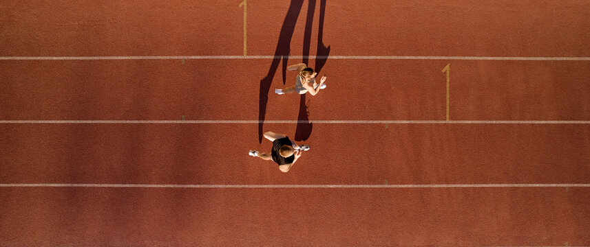 Top down view of two runners training on red running track