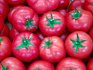 A bunch of red tomatoes with green stems