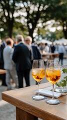 Two cocktails capture attention on the table while people socialize in the background under warm sunset tones