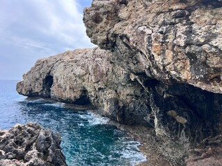 Rocky coastal cave with turquoise waters and rugged cliffs in Cyprus, capturing the dramatic natural landscape