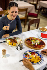 Young Woman Having Breakfast with Eggs, Bacon, and Vegetables