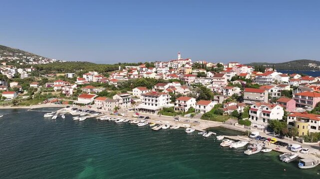 Drone captures the charming coastal village of Seget Vranjica with houses, rocky shorelines and deep blue sea extending along the Croatian coast