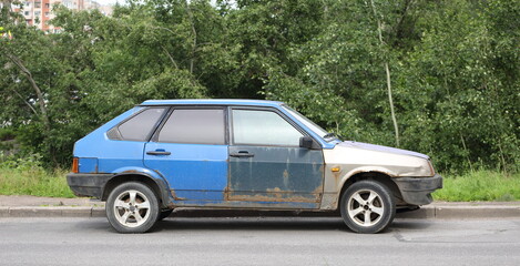 Old rusty multicolored car on the road, Kollontai Street, Saint Petersburg, Russia, July 08 2025