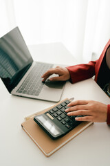 Accountant working at desk using calculator to calculate company's annual financial and tax report. financial concept