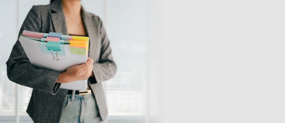 Young female employee is working with a pile of documents to search for information and check documents on the table. Document search concept.