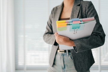 Young female employee is working with a pile of documents to search for information and check documents on the table. Document search concept.