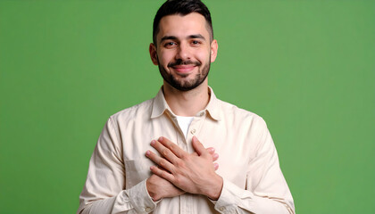 Smiling Young Man Clasping Hands Over Chest with Beard in Front of Green Background
