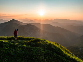 Aerial view of man on top of a mountain at sunset with mountain range in the background. Achenkirch, Tirol, Austria