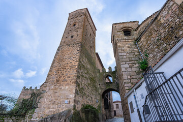 View of an ancient stone arched passageway connecting two prominent towers in the historic town of...