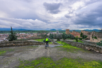 A person cycles on a high point overlooking the historic town of Trujillo Spain with its ancient...