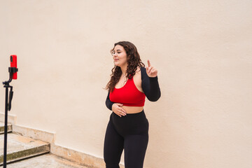 Curvy woman wearing sportswear recording online fitness class with smartphone